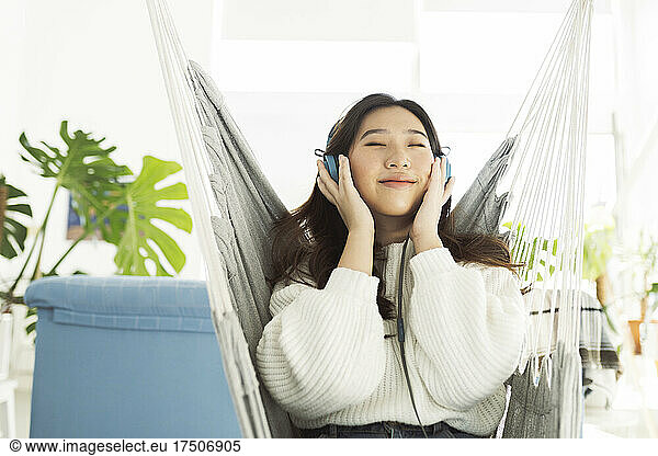 Woman listening music through headphones on hammock