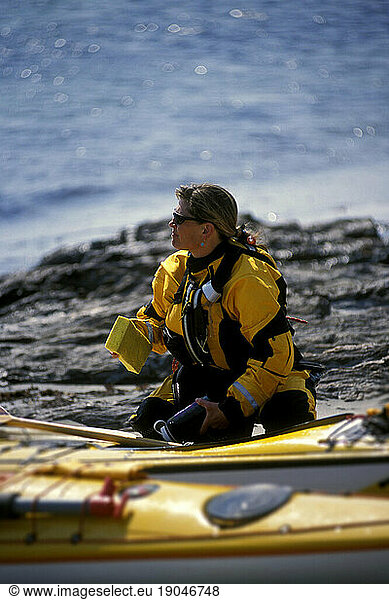 Woman loading sea kayak  Maine.