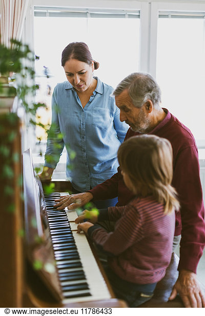 Woman looking at boy and great grandfather playing piano