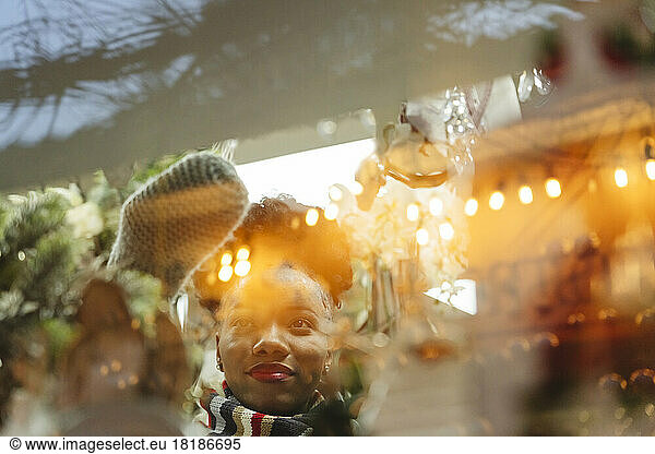 Woman looking at Christmas decorations through glass