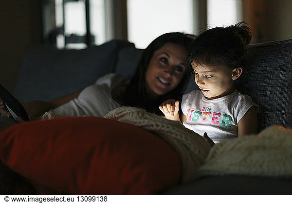 Woman looking at daughter using tablet computer at home