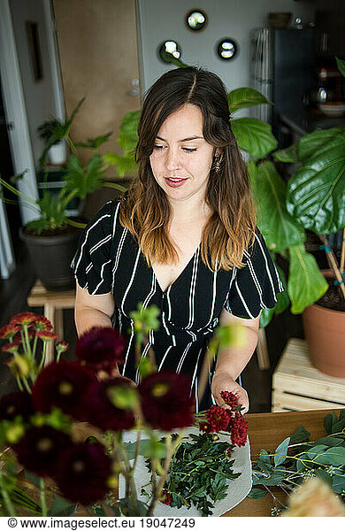 Woman looking at flowers while making floral arrangement