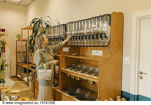 Woman looking at food dispensers arranged in organic shop