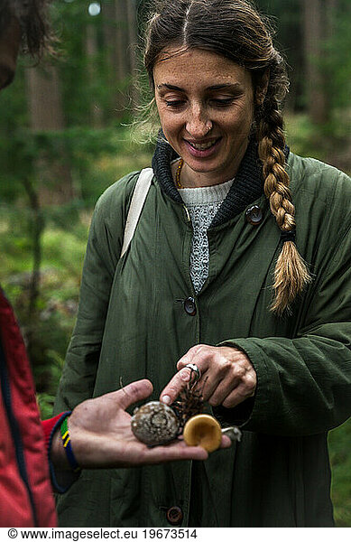 Woman Looking At Wild Mushrooms In A Forest In Scandinavia