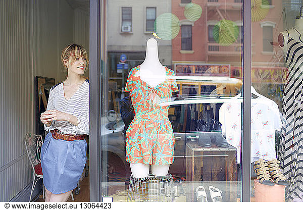 Woman looking away while leaning on store window