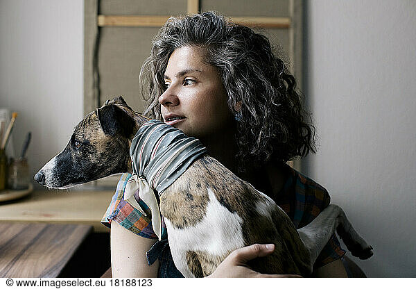 Woman looking away while sitting with dog at home