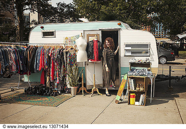 Woman looking away while standing at camper van door