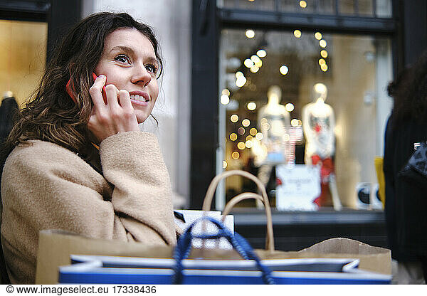Woman looking away while talking on smart phone by store