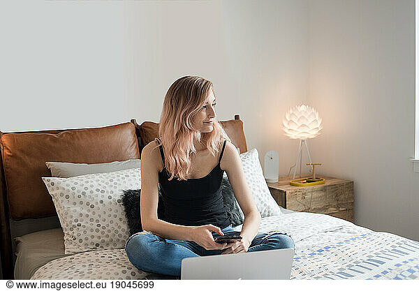 Woman looking off camera while sitting on bed