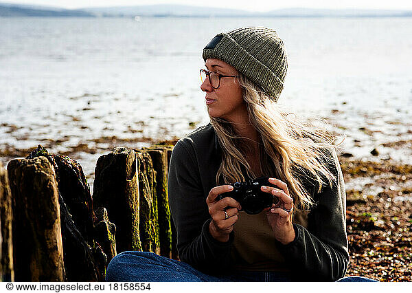 woman looking thoughtful whilst taking photos at the beach