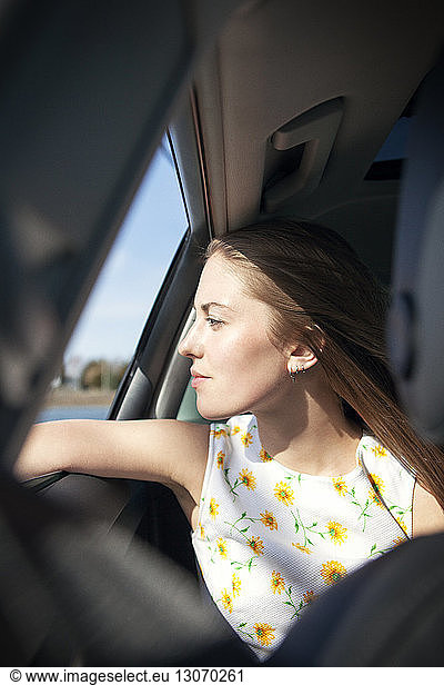Woman looking through car window while traveling