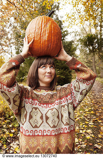 Woman looking up while carrying Halloween pumpkin