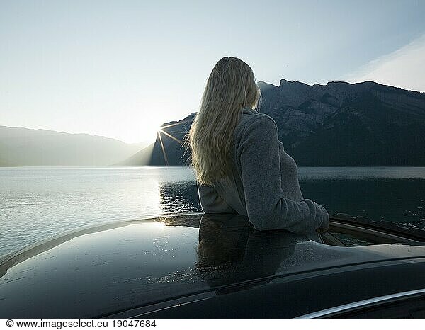 Woman looks out from car  mountain lake