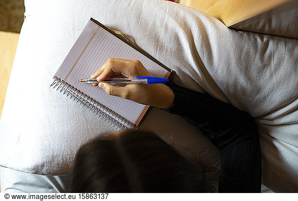 Woman lying in bed writing on her datebook.