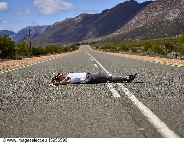 Woman lying in the middle of a road surrounded by mountains  Swellendam area  South Africa