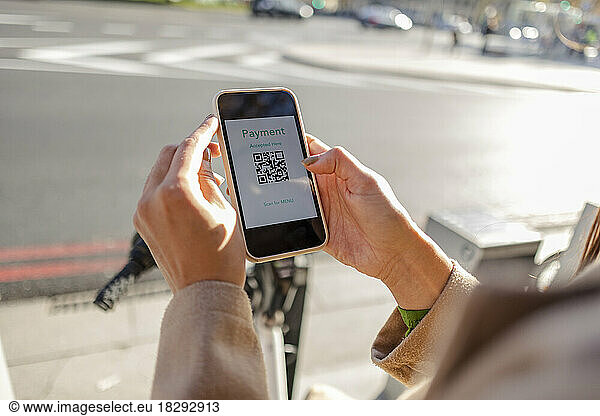 Woman making contactless payment using smart phone for renting bicycle