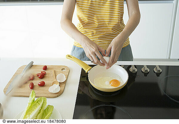 Woman making fried eggs at home