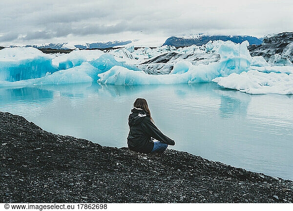 woman meditating near lake with iceberg
