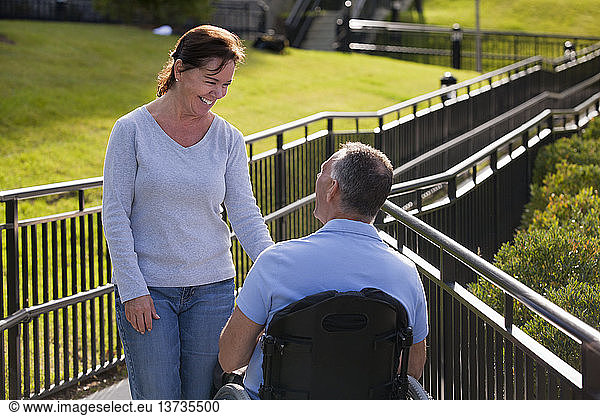 Woman meeting with husband in wheelchair with spinal cord injury on accessible ramp