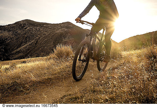 Woman mountain biking during sunset in mountains on single track