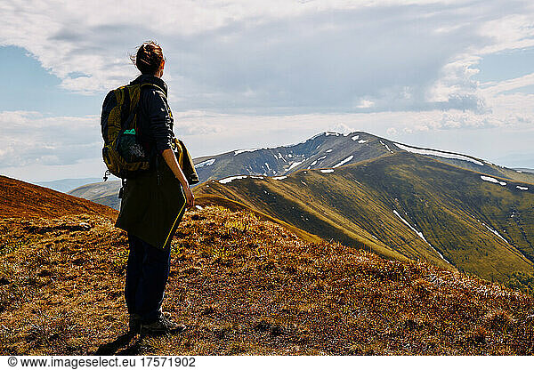 Woman mountain traveler looks at the mountain range.