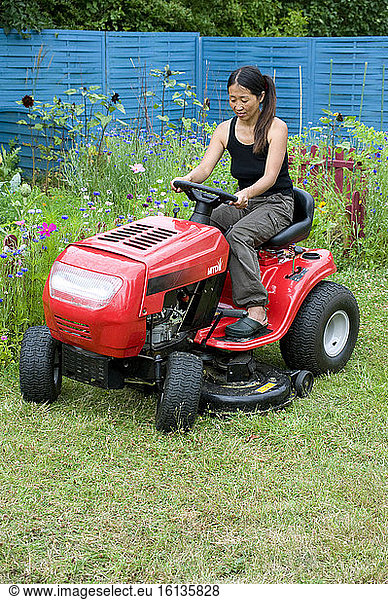Woman mowing the lawn on a riding mower