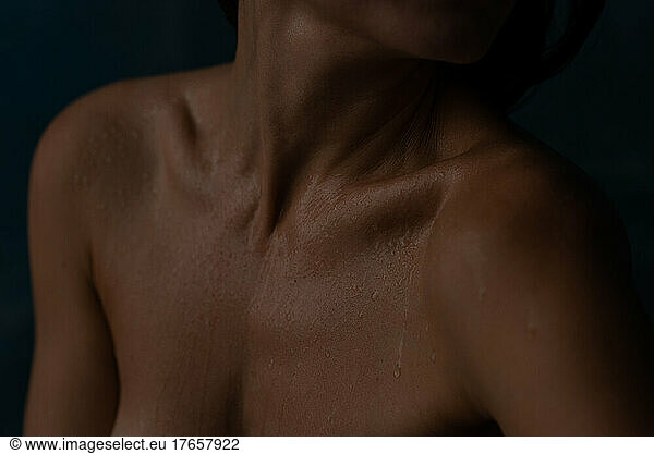 Woman neck and breast in little water drops in darkness