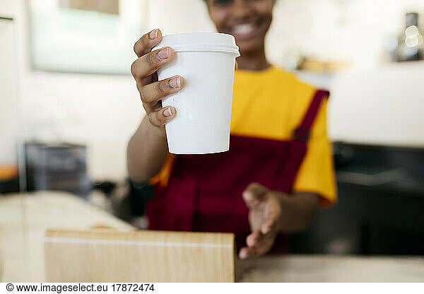 Woman offering disposable coffee cup