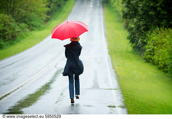 Woman on empty road with red umbrella