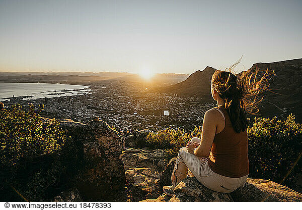 Woman on rock looking at cityscape from Lion's Head Mountain at sunrise