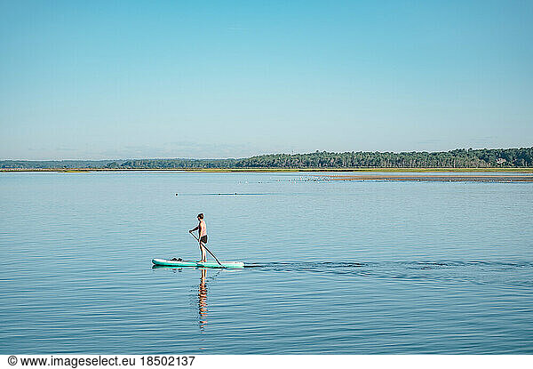 Woman on stand-up paddleboard on ocean in summer