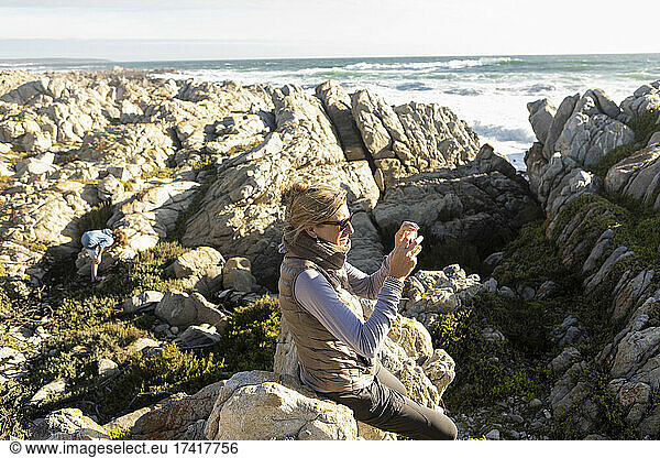 Woman on the coastline  taking pictures holding a camera
