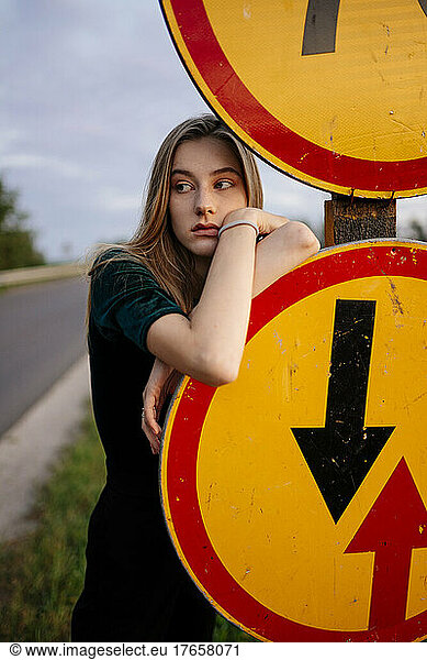 Woman on the road looking at traffic signs