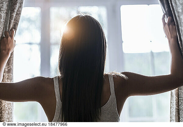 Woman opening curtains at the window