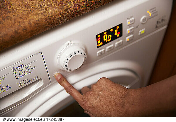 Woman operating washing machine at home
