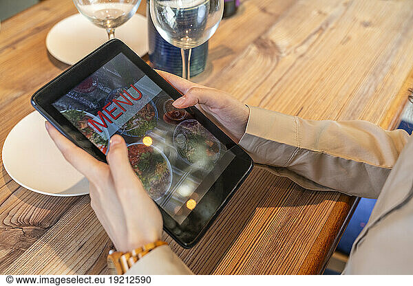 Woman ordering food using tablet PC at cafe