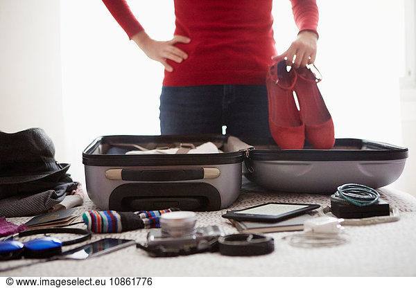 Woman packing suitcase  holding shoes  mid section
