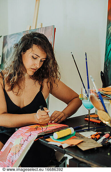 Woman painter focused on work sitting at table in her studio  close up