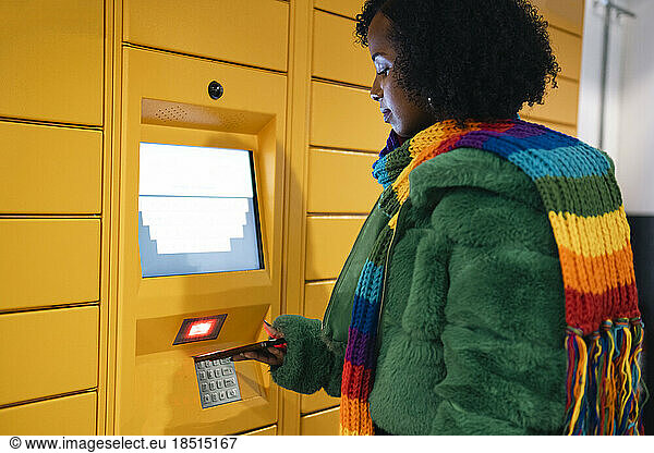 Woman paying through smart phone at ticket vending machine