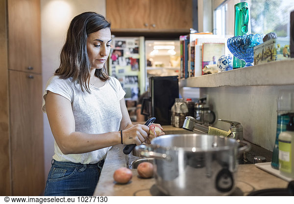 Woman peeling potato at kitchen counter