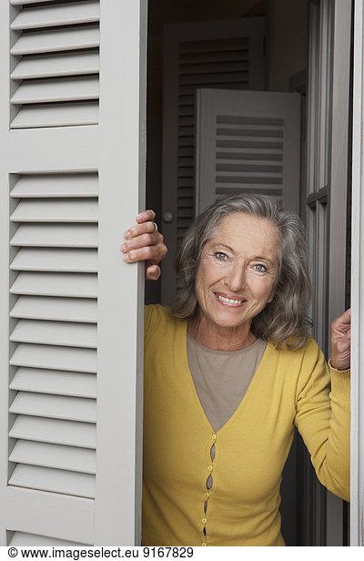 Woman peering out window shutters