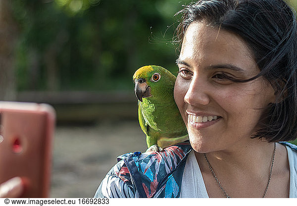 Woman performs a selfie with a parrot in the jungle of the Orinoco Delta in Venezuela