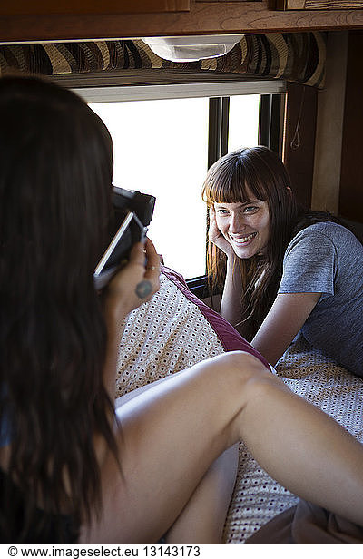 Woman photographing friend in camper van