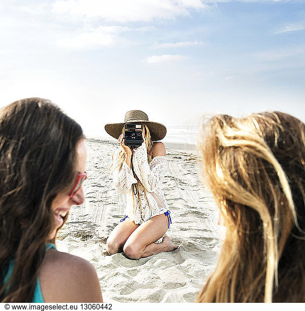Woman photographing friends at beach
