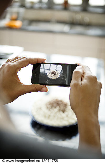 Woman photographing homemade tart with smart phone