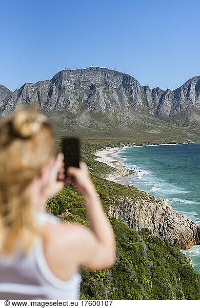 Woman photographing mountains through mobile phone