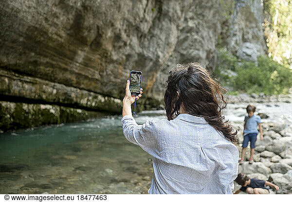 Woman photographing nature through smart phone at vacation