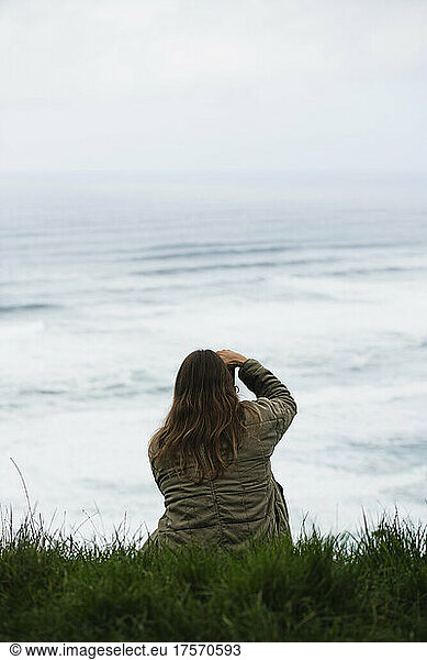 Woman photographing ocean waves from a high overlook