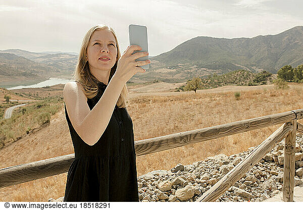 Woman photographing through smart phone on sunny day