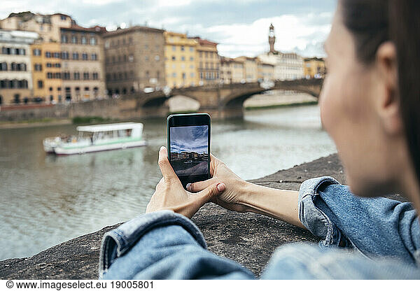 Woman photographing tourist boat sailing on river